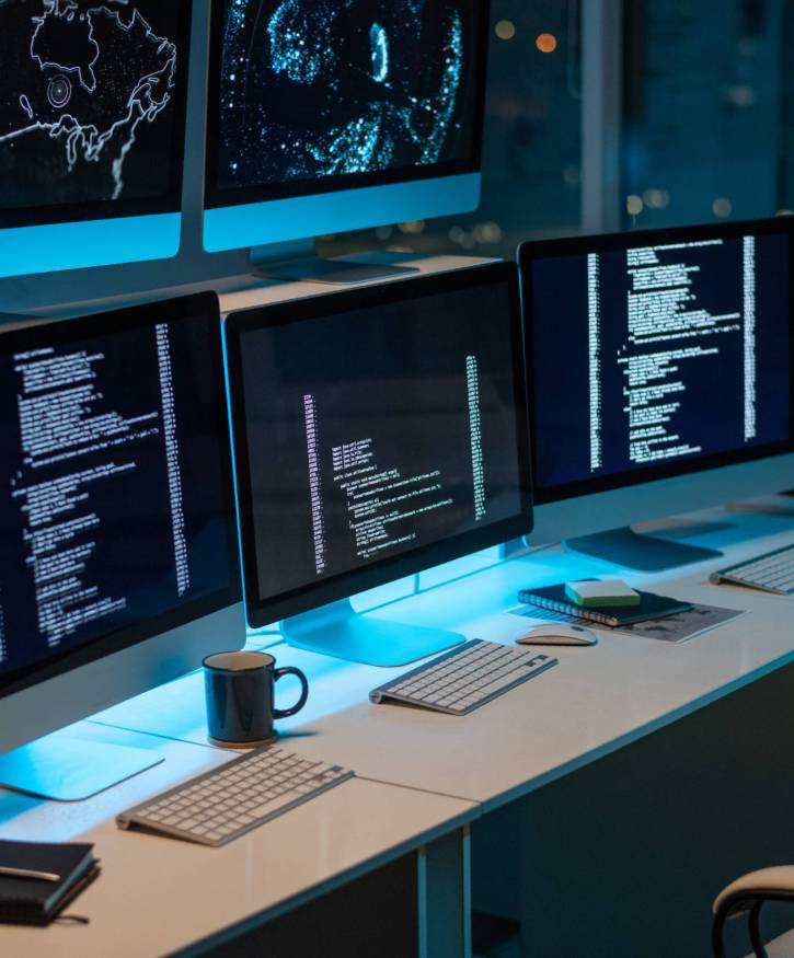 Workplace of contemporary it-engineers with three computers standing on desk in large openspace office